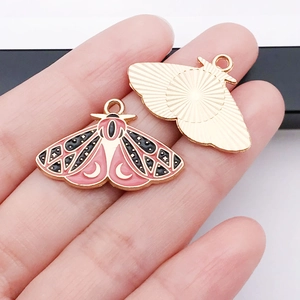 Detail of pink moth butterfly pendant with moon patterns and gold sunburst texture