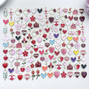 Flat lay of heart and rose charms for DIY jewelry making in pink and red oil drip finish