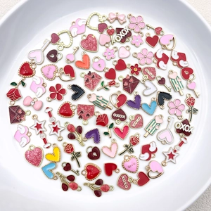 Assorted colorful enamel heart and rose charms for DIY jewelry making in a white plate