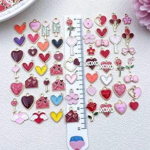 Assorted red and pink enamel heart pendants for DIY jewelry with ruler for scale