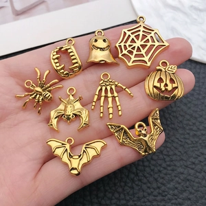 Detailed view of hand-held vintage gold Halloween alloy pendants for DIY jewelry making