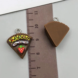 Detail view of a 3cm resin cake slice pendant with strawberry and cream toppings