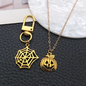 Detail of Halloween spider web keychain and pumpkin pendant necklace set in golden finish