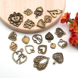 Vintage bronze alloy heart and wing pendants on a light wood plate with flowers