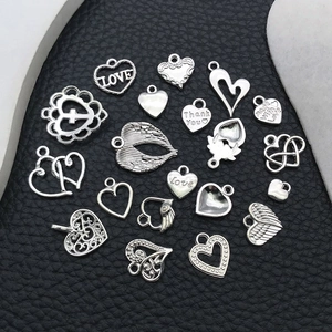 Detailed macro view of assorted silver alloy heart and wing charms on black leather