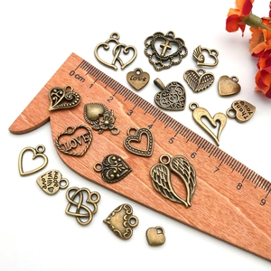 Macro view of vintage bronze alloy heart and wing pendants on white background with scale
