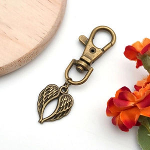 Detailed macro view of bronze alloy angel wings charm with lobster clasp attachment