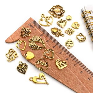 Macro shot of assorted vintage gold charms with size scale on a wooden ruler