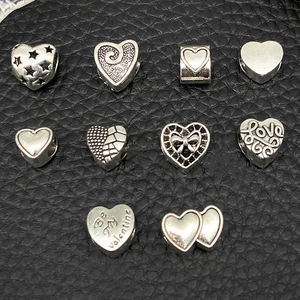 Detailed close-up of antique silver heart charms with Love and Valentine engravings