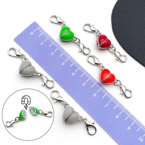 Macro detail of heart-shaped magnetic clasp connectors with metal lobster hooks for DIY jewelry