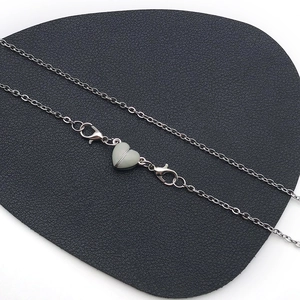 Detailed close-up of heart-shaped magnetic clasp on a silver necklace with lobster claws