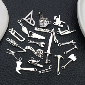 Détail de breloques d'outils en alliage argent antique incluant marteau et scie sur cuir