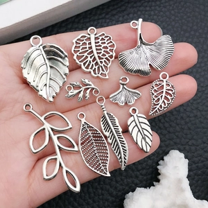 Set of vintage silver leaf alloy pendants for DIY jewelry making held in a hand