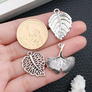 Macro shot of vintage silver leaf alloy pendants for DIY jewelry with a coin for scale