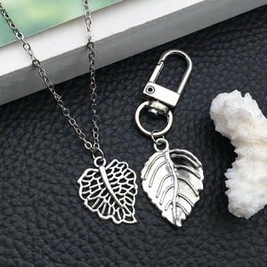 Vintage silver alloy leaf pendant necklace and charms set on a black textured background