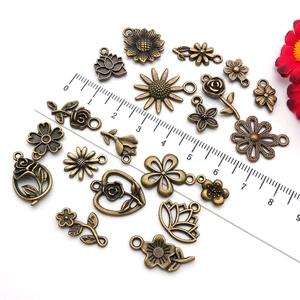 Detailed view of antique bronze alloy flower pendants with ruler for size reference