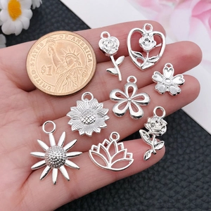 Dettaglio di vari ciondoli a fiori in argento per gioielli fai-da-te con moneta di riferimento