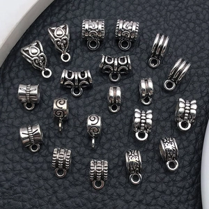 Gros plan de divers connecteurs de bijoux en alliage argenté sur fond cuir noir