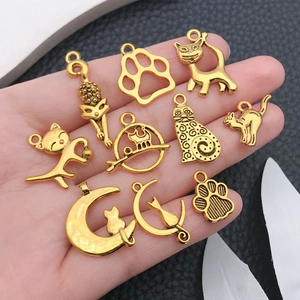 Set of 10 antique gold alloy cat charms for DIY jewelry making displayed in hand