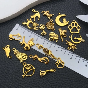 Set of golden alloy cat charms with moon and paw designs on black leather background
