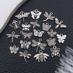 Macro detail of antique silver insect pendants for DIY jewelry making on dark leather