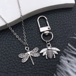 Vintage silver insect jewelry set with dragonfly pendant and bee charm on black background