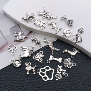 Macro shot of antique silver dog-themed DIY charms including bone and paw prints