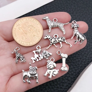 Detail view of 9 antique silver dog pendants with 1 dollar coin for size reference