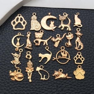 Détails de breloques chat et patte dorées disposées sur un fond de cuir grainé noir