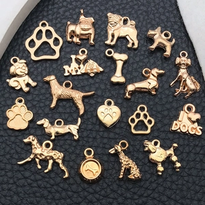 Close-up of golden alloy dog-themed charms and paw prints on a black leather background
