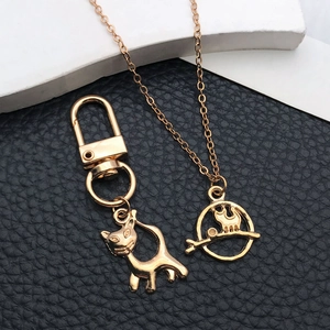 Détails de pendentifs chat dorés avec porte-clés et collier sur fond de cuir noir