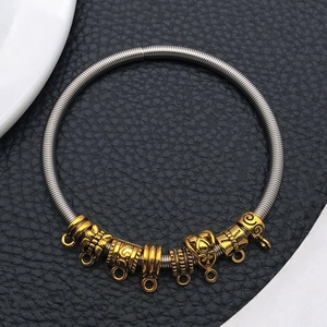 Macro detail of DIY spring metal bracelet with antique gold beads and charm ring connectors