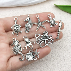 Assorted vintage silver ocean theme alloy charms including starfish and turtles on a palm