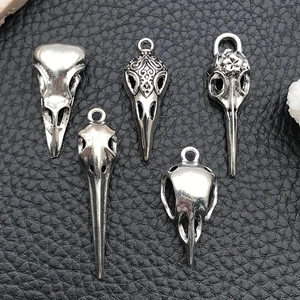 Detailed macro shot of five gothic bird skull pendants on black leather background