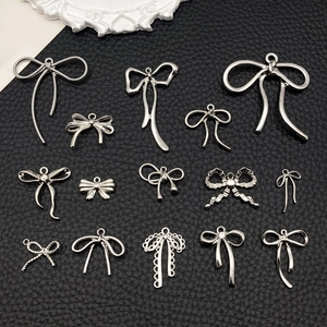 Colección de colgantes de lazo plateados para joyería DIY sobre superficie de cuero negro