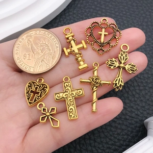 Collection of seven vintage gold alloy cross pendants shown with a coin for scale