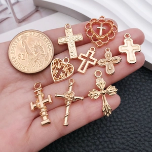 Antique rose gold alloy heart and cross charms shown with a coin for scale
