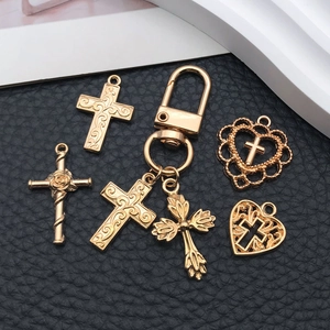 Detail of vintage gold alloy cross and heart charms with floral engraving for DIY jewelry