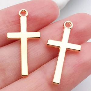 Detail of two vintage gold cross pendants held by hand for DIY jewelry making