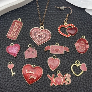 Detailed flat lay of red and pink heart enamel charms and Valentine pendants on black leather