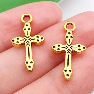Macro shot of vintage gold cross charm with black engraved totems and ring bail
