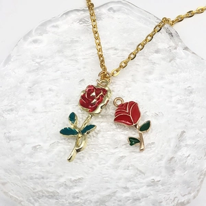Set di collana e ciondolo dorati con rose in smalto rosso e foglie verdi