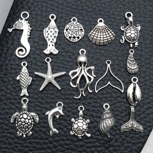 Macro view of fifteen different antique silver marine charms on a black leather background