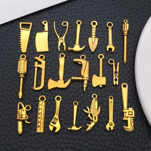 Detailed set of 20 miniature golden alloy hardware tool charms on black leather background