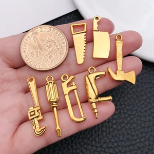 7-piece gold alloy miniature tool pendant set with coin for size reference