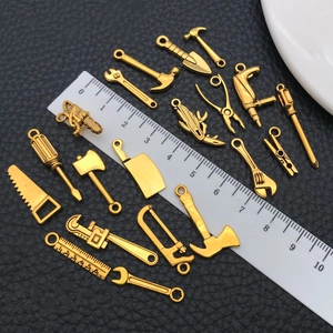 Macro detail of miniature gold-plated alloy hardware tool pendants with a scale ruler