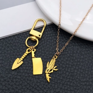 Detailed close-up of golden alloy shovel and knife pendants on a textured black background
