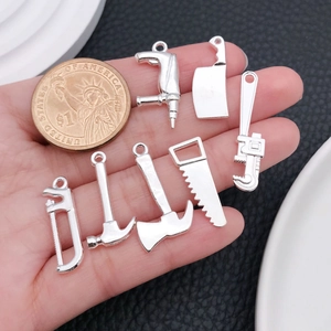 Gros plan de 7 breloques d'outils en alliage d'argent DIY tenues dans la main