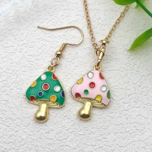 Detail of green and pink mushroom enamel charms with colorful dots and golden texture