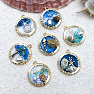 Detail of 7 sea-themed enamel charms with pearls and starfish on white background